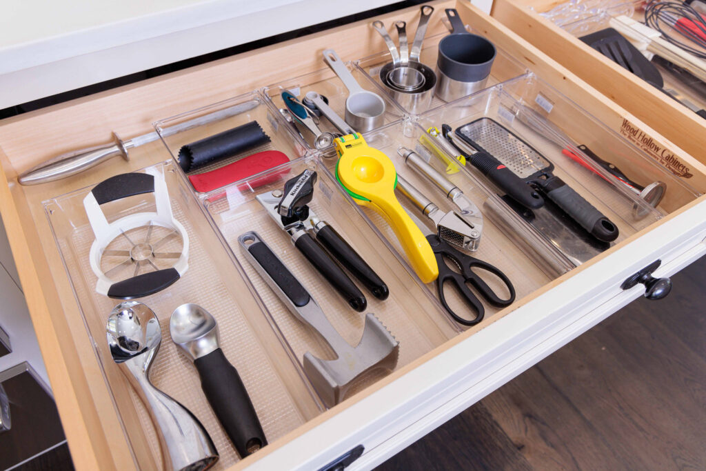 A kitchen utensil drawer organized by UpTown Concierge with clear acrylic drawer organizers. 