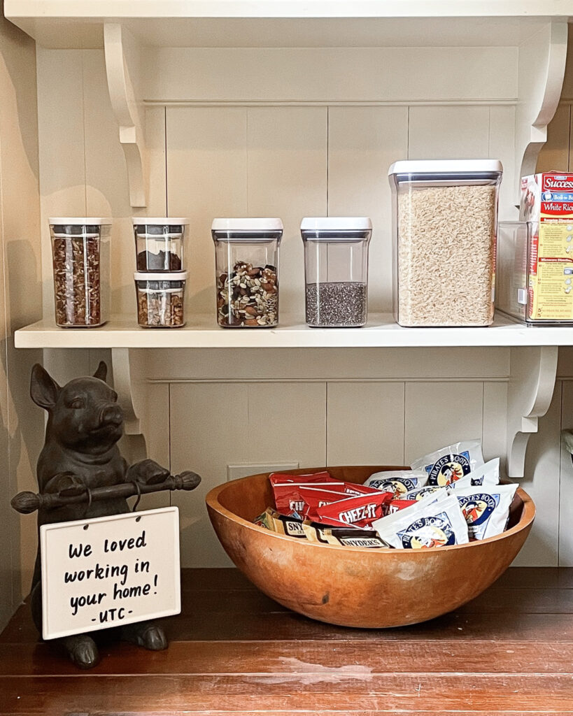 Dry goods decanted in OXO Good Grips Pop Canisters, organized on a shelf in a pantry with a handwritten note that reads, "We loved working in your home! - UTC" 
