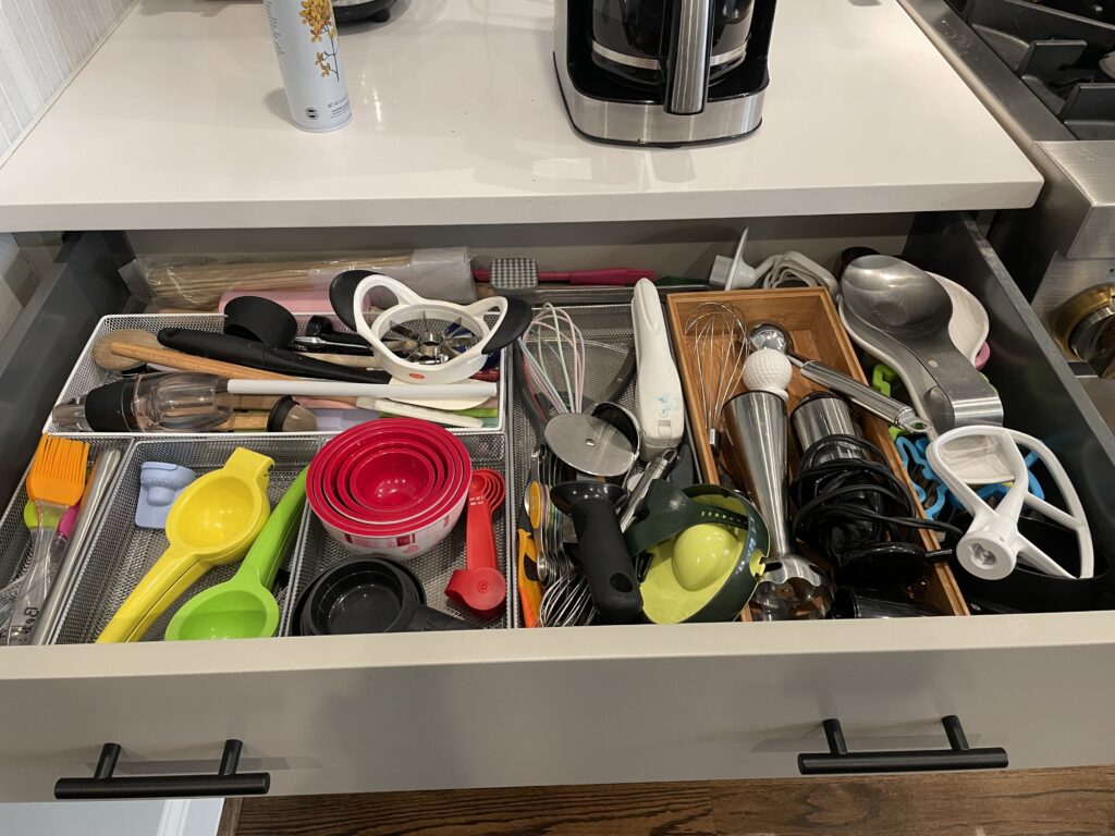 Unorganized, messy, cluttered kitchen utensil drawer.