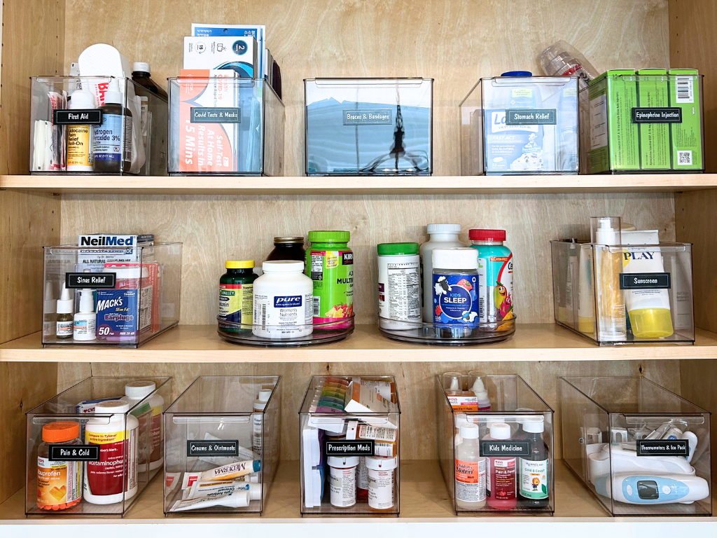 medicine cabinet organized with clear bins and black labels