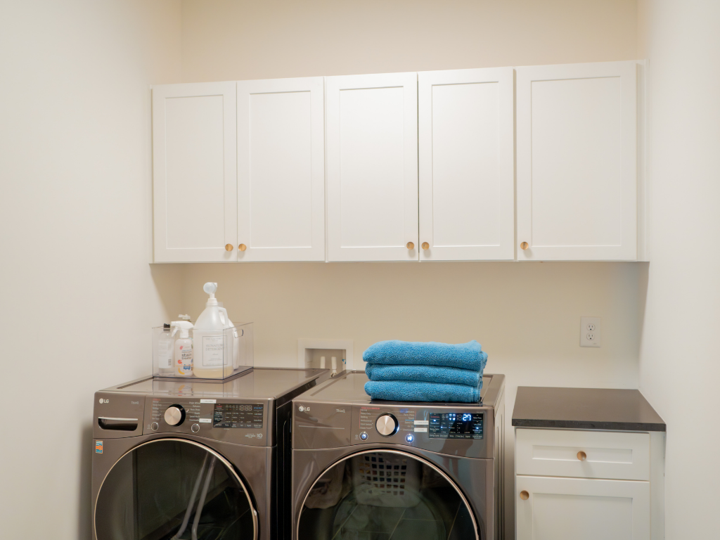 Clean, decluttered, and organized laundry room with washer and dryer and white cabinets. 