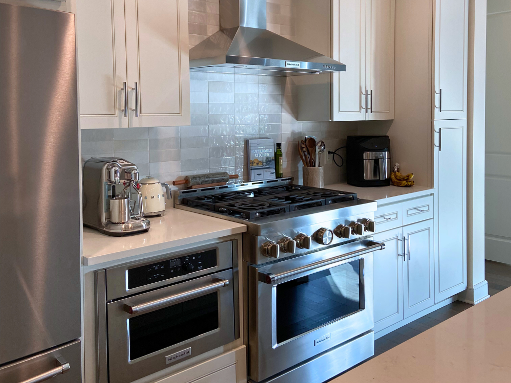 Clean kitchen with white countertops and cabinets ready for summer fun! New Blog post Why Your Home Gets Messier in the Summer 